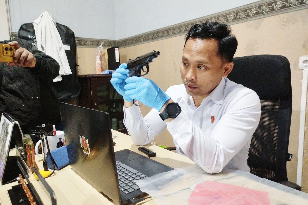 Penyidik Satreskrim Polres Bangkalan menunjukkan pistol makarov saat menginterogasi Abdus Syukur di Mapolres Bangkalan, Selasa (24/6/2025).
