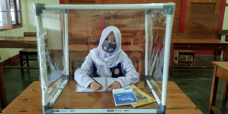 Seorang siswa mencoba duduk di meja belajar yang ditambahkan plastik di sekelilingnya di SMAN 4 Kota.Sukabumi, Jawa Barat, Rabu (8/7/2020).