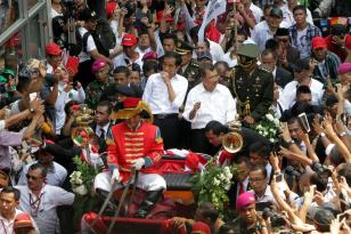 Presiden Joko Widodo dan Wakil Presiden Jusuf Kalla (Jokowi-JK), menaiki kereta kencana melintas di Jalan MH Thamrin, Jakarta Pusat, Senin (20/10/2014). Kirab yang merupakan rangkaian dari acara Syukuran Rakyat Salam 3 Jari, ini digelar usai pelantikan pasangan tersebut. Jokowi-JK diarak melintasi pusat Ibu Kota menuju Istana Negara. TRIBUNNEWS/HERUDIN