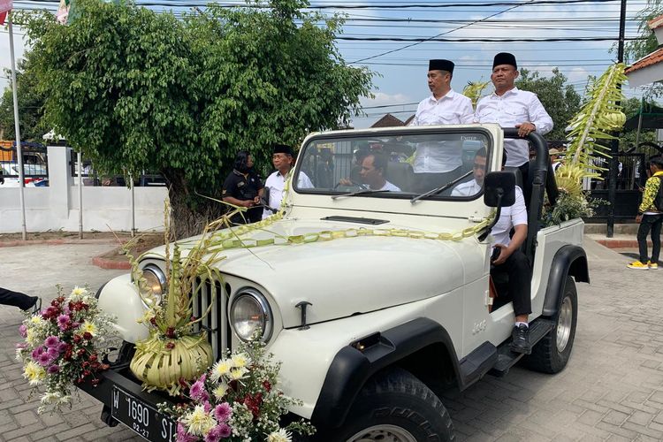 Bakal pasangan calon bupati dan wakil bupati, Hari Wuryanto-Purnomo Hadi menumpang mobil jeep dihias dan diarak massa bak pengantin saat mendaftar di Komisi Pemilihan Umum Kabupaten Madiun, Jawa Timur, Rabu (28/8/2024).
