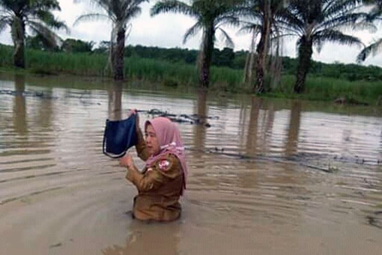 Yuliana, guru SDN 3 Bandar Agung, Lampung Utara nekat menerjang banjir setinggi dada untuk pergi mengajar. (Foto: tugiadr/facebook)