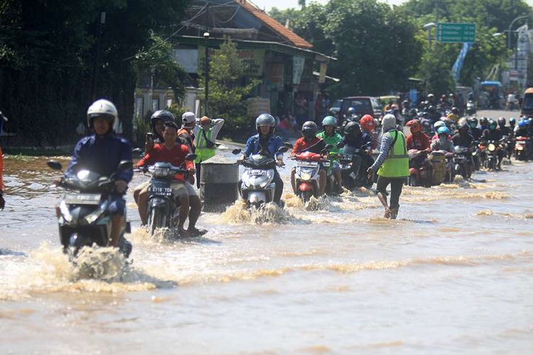 Kendaraan bermotor menerobos banjir yang menggenangi kawasan Jalan Raya Pantura Kraton, Pasuruan, Jawa Timur, Selasa (14/4/2020). Banjir sedalam satu meter yang hampir melumpuhkan Jalur Pantura tersebut terjadi akibat meluapnya Sungai Welang setelah diguyur hujan sejak Senin (13/4) malam.