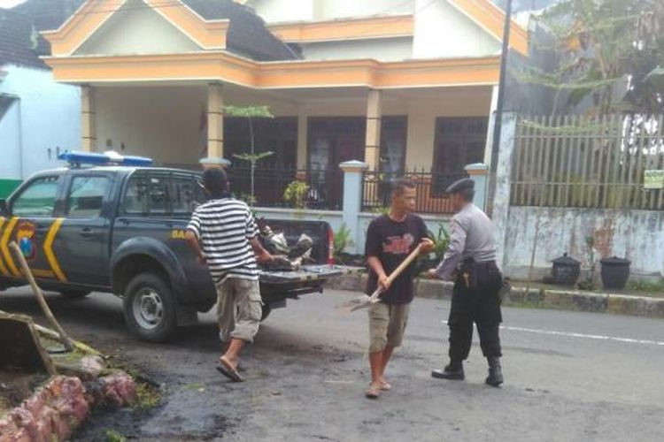 Polisi bersama warga menaikkan sampah dari selokan dan dinaikkan ke mobil patroli Polisi (26/02/2017)