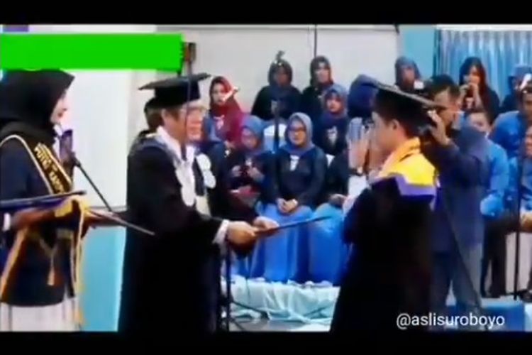 Seorang mahasiswa sedang berjoget di depan dekan ketika prosesi wisuda.