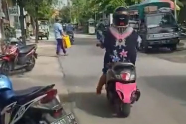 Tangkapan layar video yang memperlihatkan seorang perempuan, sedang mengendarai sepeda motor dengan pelat nomor ditutupi celana dalam di Lamongan. 