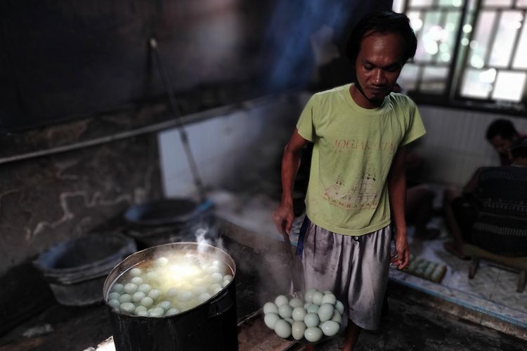Pekerja mengambil telur asin yang baru saja direbus di rumah produksi di Jalan Pangeran Diponegoro Brebes sebelum dijajakan ke sejumlah toko oleh-oleh khas di sepanjang pantura Brebes, Jawa Tengah, Rabu (11/4/2023) 