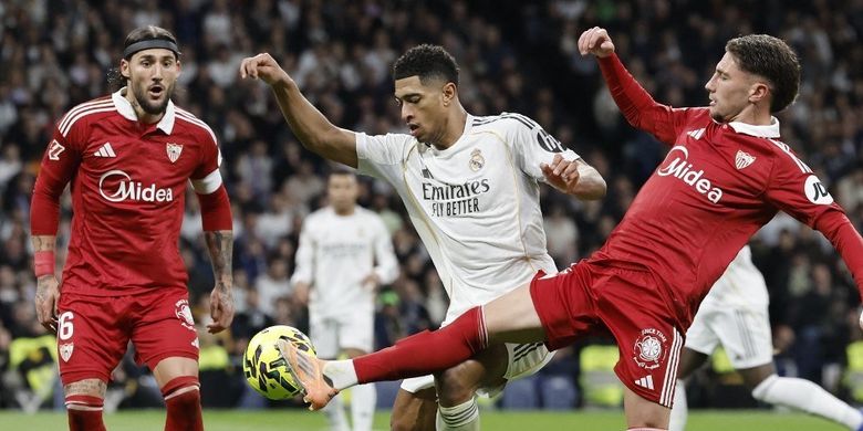Jude Bellingham (tengah) dibayangi Nemanja Gudelj dan Jose Angel Carmona dalam pertandingan sepak bola Liga Spanyol antara Real Madrid CF vs Sevilla FC di Stadion Santiago Bernabeu di Madrid pada 20 Desember 2025. (Foto oleh Oscar DEL POZO / AFP)