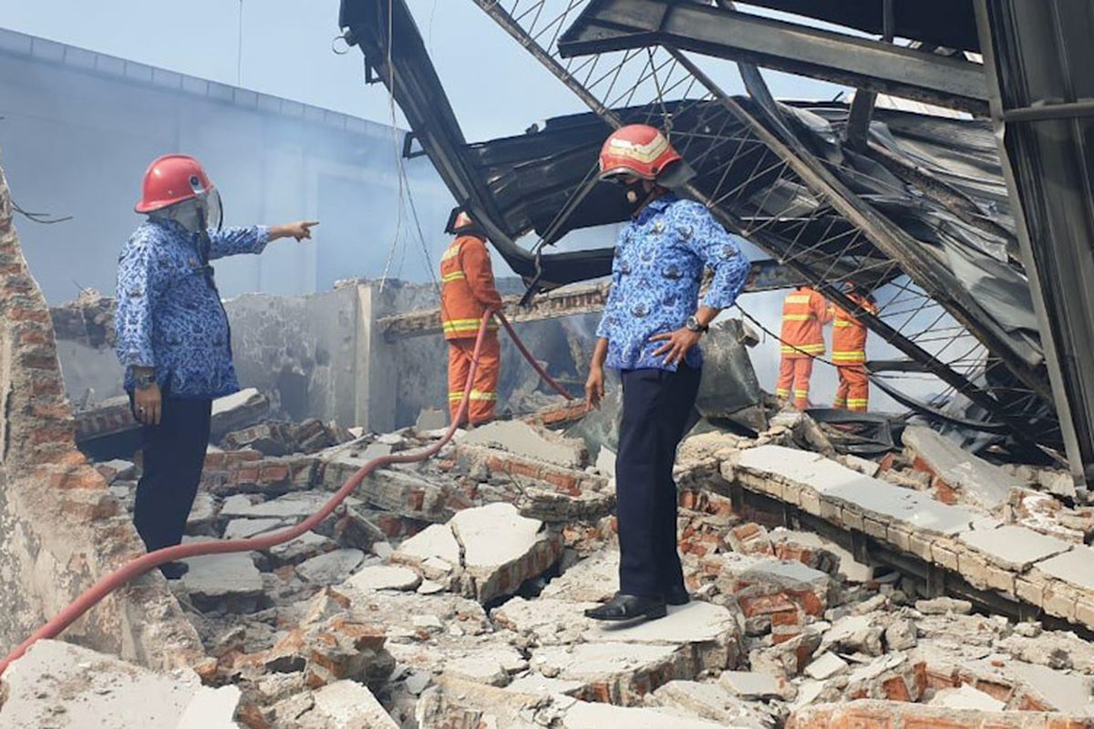 Petugas Damkarla Gresik melakukan pembasahan di lokasi kebakaran, untuk memastikan api sudah benar-benar padam di gudang PT Rajasa Putra Jaya Perkasa, Kamis (17/3/2022).