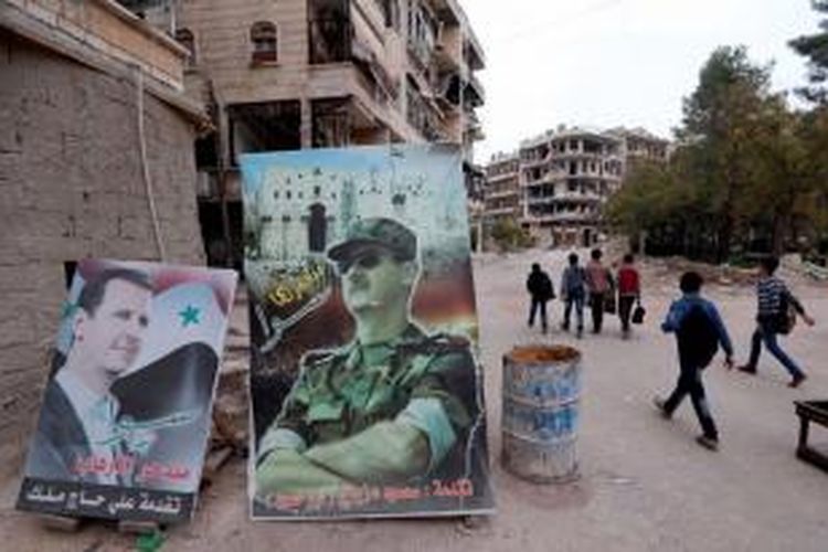 Anak-anak berjalan di dekat poster Presiden Suriah Bashar al-Assad di Sleiman al-Halabi, Aleppo, 16 November 2014.