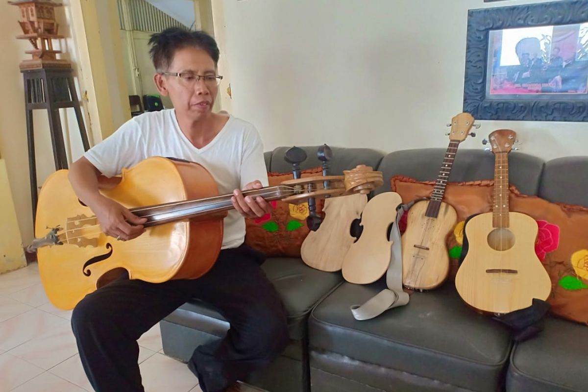 Erwan Prasetyo, seniman keroncong asal Madiun memainkan alat musik Cello hasil karyanya yang dibuat dari bahan kayu bekas peti kemas, Jumat ( 14/9/2018).