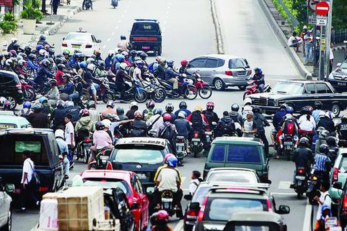 Puluhan sepeda motor berhenti di perempatan Jalan Matraman Raya, Jakarta Timur, Rabu (28/7), saat lampu pengatur lalu lintas berwarna merah. Kebiasaan pengendara sepeda motor yang berhenti tidak di belakang garis sering kali menghambat arus lalu lintas yang sedang bergantian jalan.