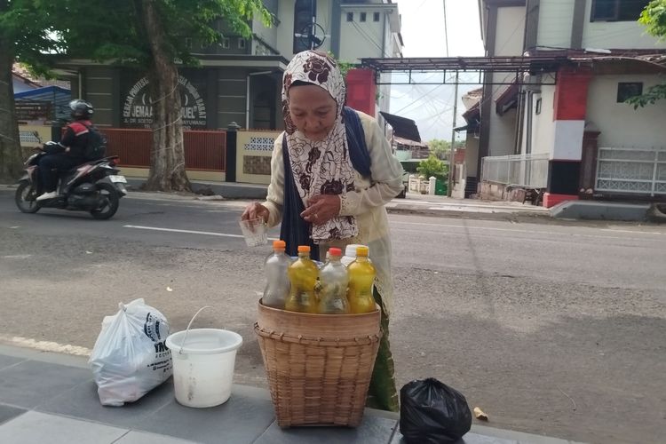 Parmi melayani pembeli jamu dengan cekatan di area Taman Blambangan Banyuwangi, Jumat, (10/1/2025). 