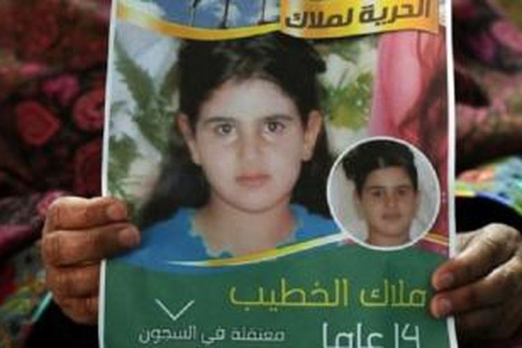 Ali Al Khatib dan istrinya Khawla, pada 27 Januari 2015, memperlihatkan sebuah poster berisi foto putri mereka yang masih berusia 14 tahun, Malak, yang menjadi tahanan perempuan Palestina termuda, yang dihukum Israel dua bulan penjara karena melemparkan batu kepada tentara Israel.