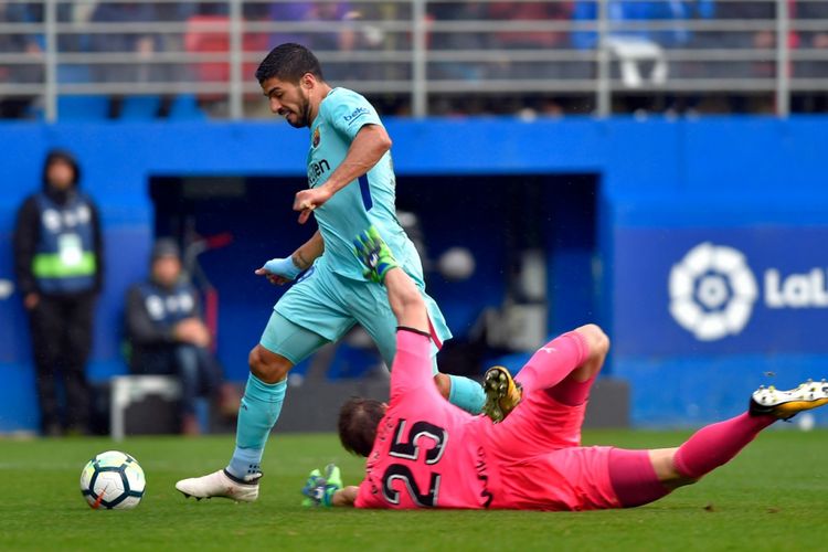 Luis Suarez Suarez mengecoh kiper Marko Dmitrovic saat Barcelona bertandang ke markas Eibar dalam pertandingan pekan ke-24 Divisi Primera La Liga Spanyol, Sabtu (17/2/2018).