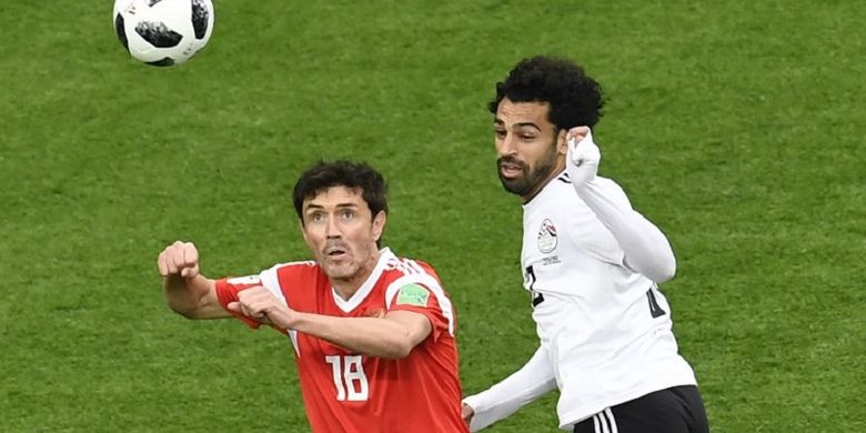 Yuri Zhirkov dan Mohamed Salah mencoba menyundul bola pada pertandingan Rusia vs Mesir di St. Petersburg, 19 Juni 2018. 