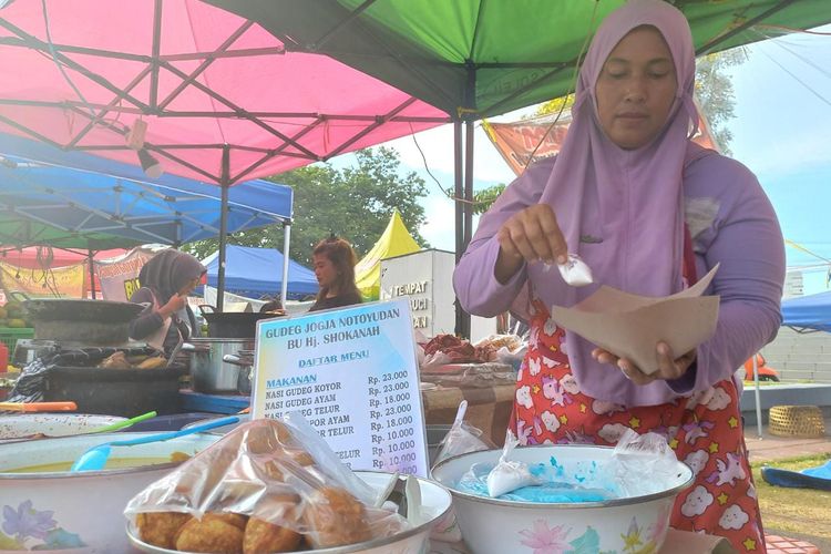 Salah satu penjual ketan biru dan kue coro santan di Aloon-Aloon Masjid Kauman Semarang sedang melayani pembeli, Sabtu (25/3/2023).