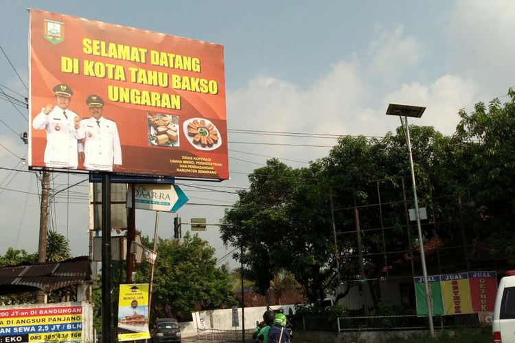 Papan reklame berwarna merah bertuliskan Selamat Datang di Kota Tahu Bakso Ungaran berdiri di Jalan Letjen Suprapto akses Tol Ungaran. 