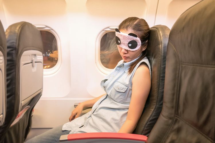 Ilustrasi seorang perempuan tidur di pesawat
