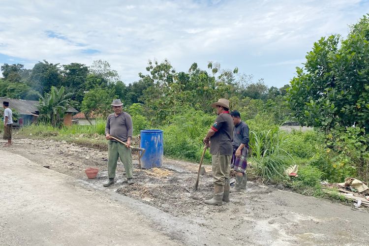 Warga Desa Kombangan bergotong royong memperbaiki jalan penghubung dua desa sekaligus akses ke rumah Bupati Bangkalan, Senin (19/5/2025). 