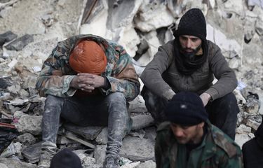 Korban gempa Suriah duduk di atas reruntuhan bangunan di Aleppo, Suriah, Selasa (7/2/2023). Gempa di Turki atau Turkiye dan Suriah bermagnitudo 7,8 pada Senin (6/2/2023), sejauh ini menewaskan lebih dari 5.000 orang.