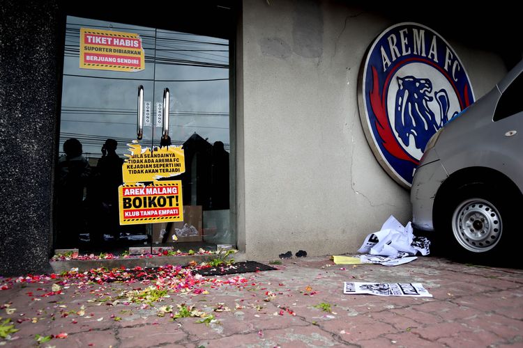 Taburan bunga dan poster yang ditempel suporter Arema, Aremania dan masyarakat saat melakukan aksi damai terkait Tragedi Kanjuruhan 1 Oktober lalu yang ditujukan kepada manajemen PT Arema Aremania Bersatu Berprestasi Indonesia di depan Store Arema FC Malang, Minggu (15/1/2023) siang.