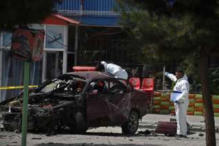 Petugas kepolisian memeriksa bangkai mobil yang menjadi korban serangan bom di dekat kedutaan besar AS di Kabul, Afganistan, Senin (15/8/2016).