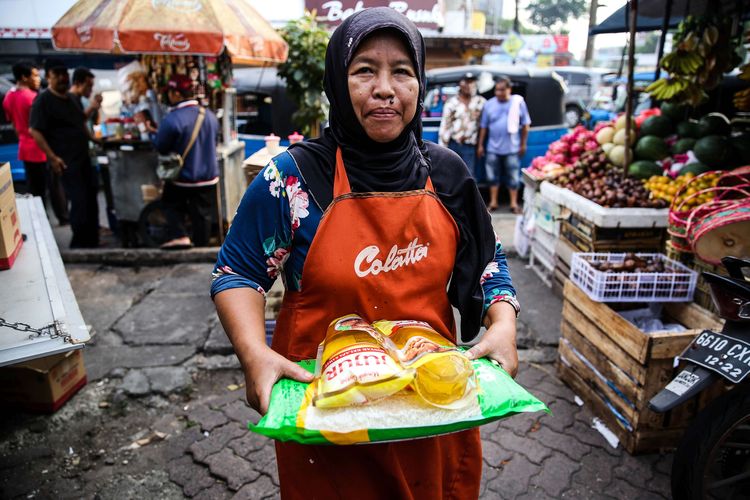 Seorang warga membawa bahan pokok berupa minyak, beras dan gula saat operasi pasar stok pangan di Pasar Rawamangun, Jakarta Timur, Kamis (19/3/2020). Perum Bulog bekerja sama dengan Sugar Group Companies menggelar kegiatan operasi pasar pangan dalam rangka menjamin ketersediaan bahan pangan pokok, serta menjaga stabilitas harga ditengah kekhawatiran masyarakat akibat pandemi virus Corona atau Covid-19. Operasi pasar stok pangan akan berlangsung selama seminggu di beberapa pasar untuk wilayah DKI Jakarta dan Banten.