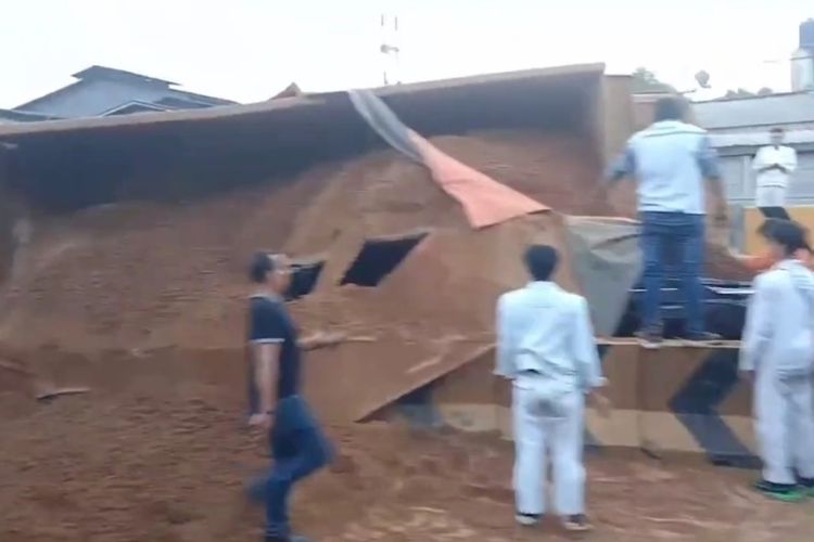 Tangkapan layar video truk bermuatan tanah terguling dan menimpa mobil pribadi di exit tol Karawang Barat, Karawang, Jawa Barat, Rabu (30/7/2025).