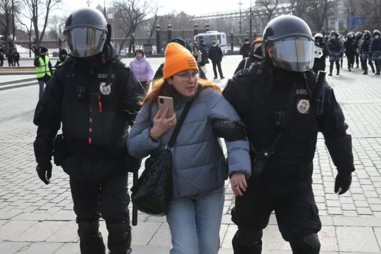 Polisi Rusia menahan seorang wanita selama demonstrasi tanpa sanksi di Lapangan Manezhnaya di depan Kremlin, 13 Maret 2022, di Moskwa.