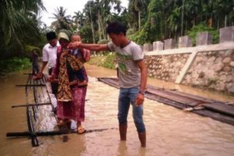 Warga melintas di lokasi banjir Desa Rayeuk Pange, Kecamatan Pirak Timu, Aceh Utara, Senin (28/9/2015). Hujan deras dan meluapnya Sungai Keureuto dan Peuto di kawasan itu mengakibatkan banjir dan merendam tiga kecamatan di Aceh Utara