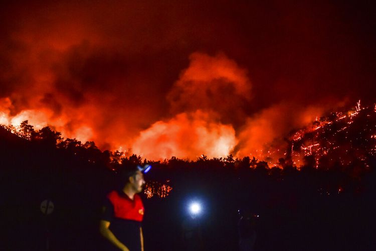 Seorang pria pergi saat api semakin membesar di daerah Hisaronu, Turki, Senin, 2 Agustus 2021.