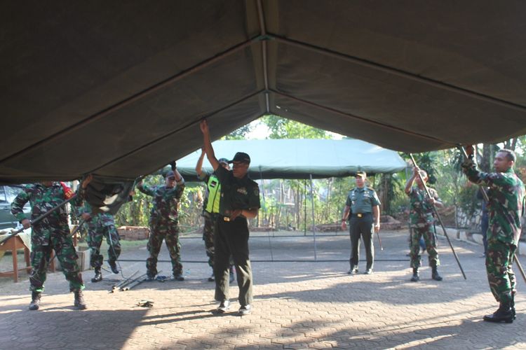 Sejumlah personil TNI dari Kodim 0608 Cianjur mendirikan dua tenda peleton di halaman SDN Pancawangi Cilaku, Cianjur, Jawa Barat, Rabu (11/09/2019) pagi. Dua tenda berukuran besar itu difungsikan sebagai kelas darurat puluhan siswa sekolah tersebut yang selama dua bulan terakhir harus belajar di halaman sekolah akibat kelas rusak dan ambruk.