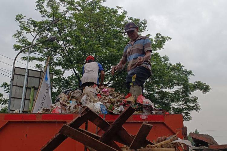Dua petugas kebersihan saat mengangkut sampah yang mengendap di Pasar Bantargebang, Kecamatan Bantargebang, Kamis (7/12/2023). Sampuh itu diangkut ke dalam bak truk sampah milik Pemkot Bekasi untuk selanjutnya dibuang ke tempat pembuangan akhir (TPA) Sumur Batu.