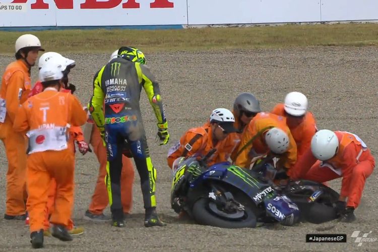 Pembalap Yamaha, Valentino Rossi, menyaksikan para marshal di Sirkuit Twin Ring Motegi berusaha mengangkat motornya setelah ia mengalami crash di pagelaran MotoGP Jepang 2019, Minggu (20/10/2019).
