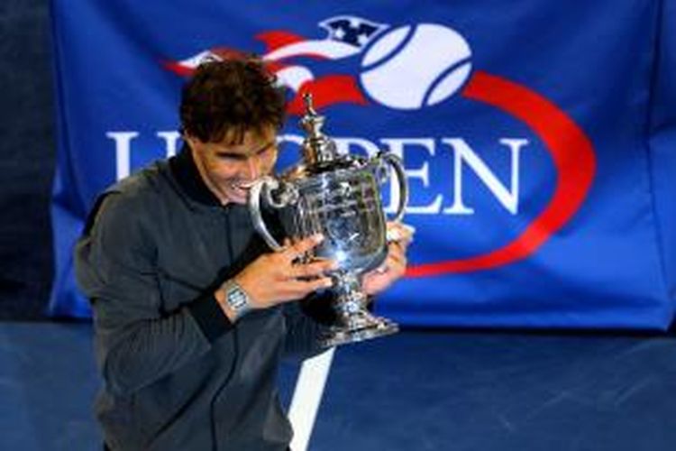 Petenis Spanyol, Rafael Nadal menggigit trofi juara US Open, setelah berhasil memenangi laga final melawan Novak Djokovic dari Serbia, di USTA Billie Jean King National Tennis Center, New York, Senin (9/9/2013).