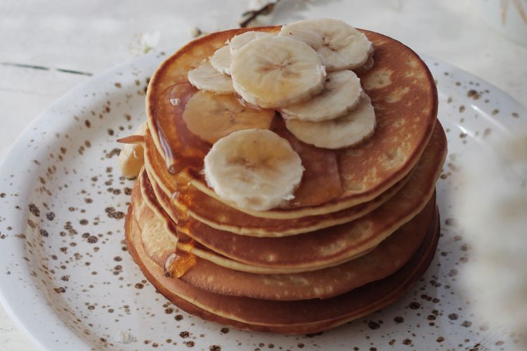 Ilustrasi pancake dengan topping pisang dan sirup maple. 
