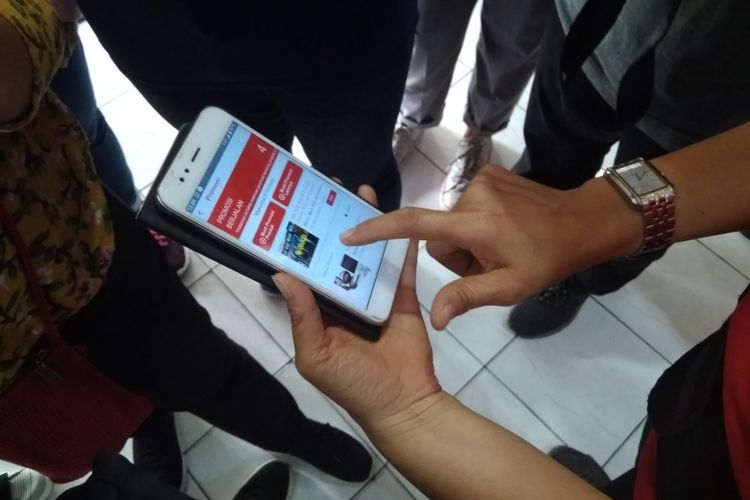 Yohana menunjukkan cara menggunakan aplikasi AYO SRC di smartphone miliknya