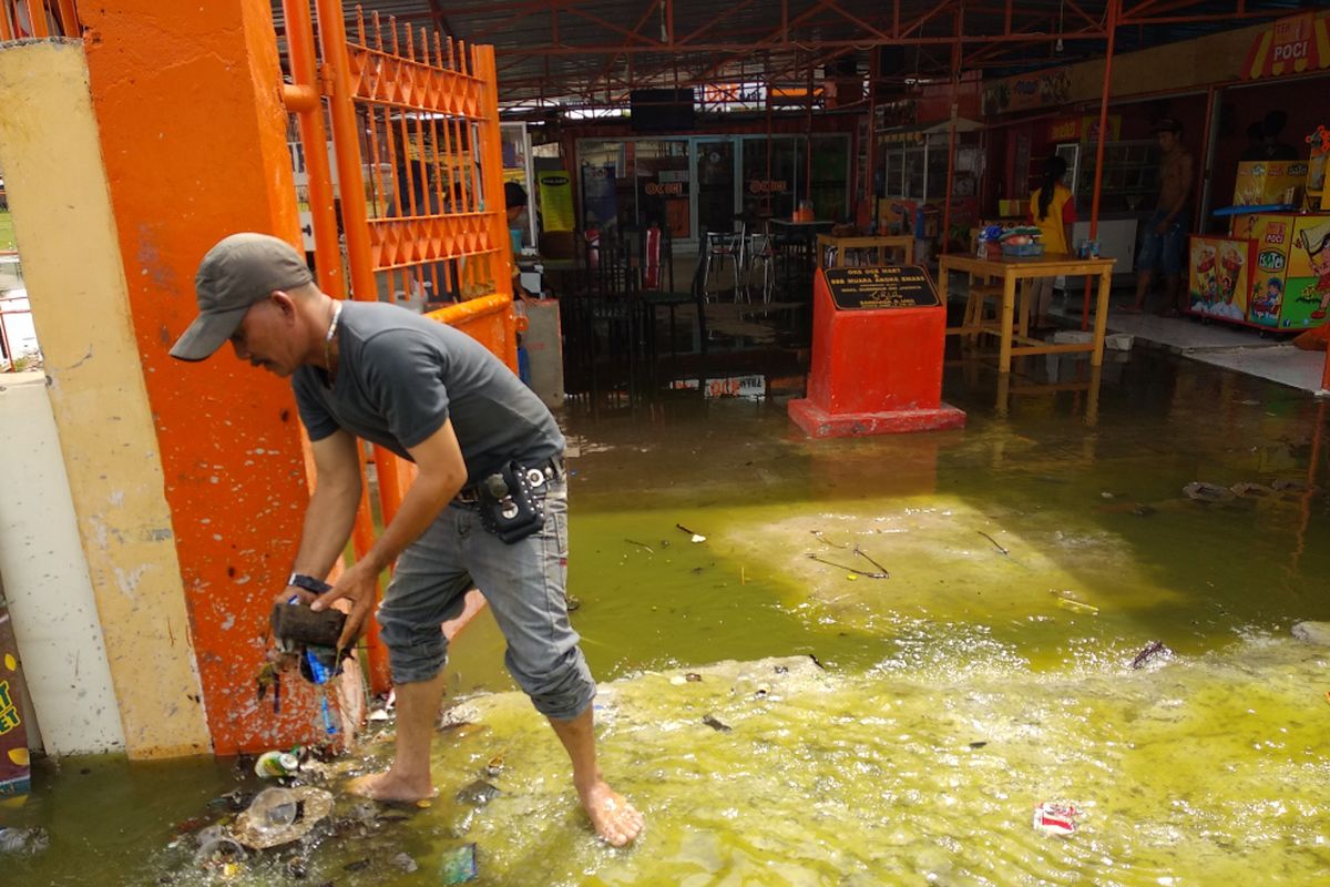Warga membersihkan sampah yang terbawa air rob yang masuk ke dalam OK OCE Mart Muara Angke, Jakarta Utara, Selasa (5/12/2017). Air laut menjebol dinding pembatas dan membuat sebagian Muara Angke tergenang air.