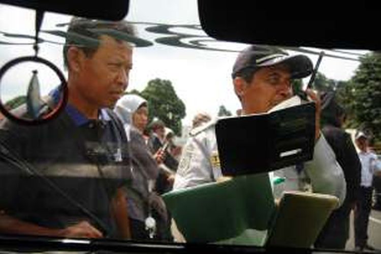 Seorang petugas Dinas Lalu Lintas Angkutan Jalan (DLLAJ) Kota Bogor memberhentikan seorang sopir angkot dalam sebuah operasi penertiban di Simpang Mall BTM, Selasa (27/9/2016).