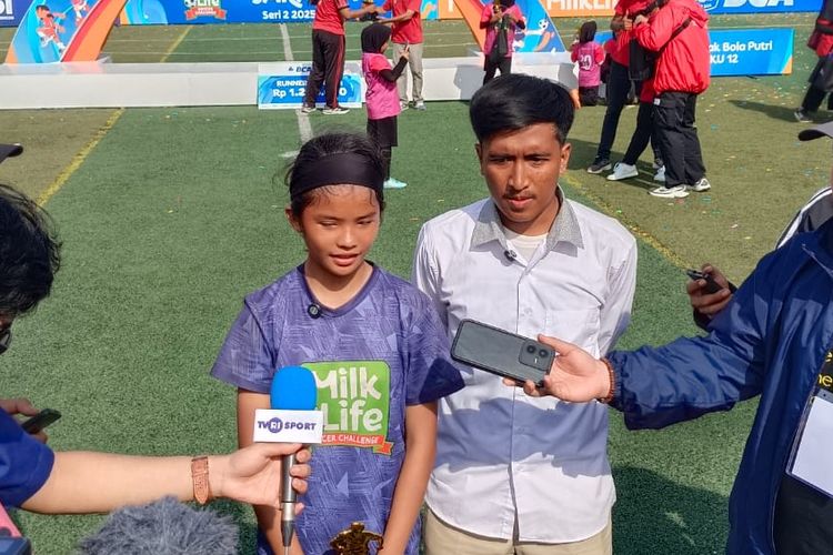 Pelatih SDN Mampang 3, Abdurahman Lesmana, menemani pemainnya, Celsin Jumei Darwati Hulu, usai juara MilkLife Soccer Challenge (MLSC) Jakarta Seri 2 2025-2026, Minggu (15/2/2026).