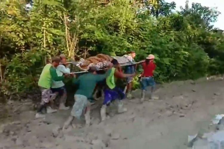 Tangkapan layar video warga Kabupaten Jombang, Jawa Timur, menandu jenazah di jalan licin dan berlumpur.