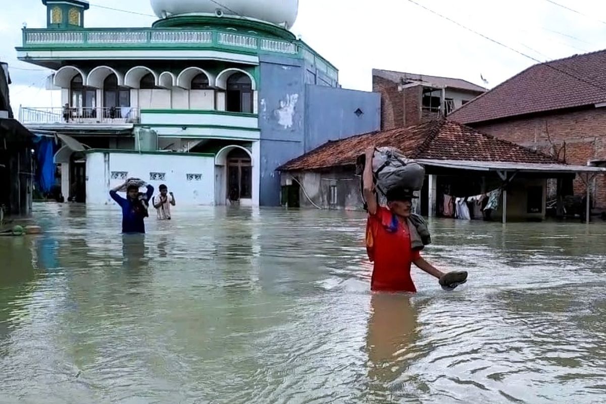 Warga Desa Cangkring, Kecamatan Karanganyar, Kabupaten Demak, melintas banjir, Minggu (17/3/2024) sore. (KOMPAS.COM/NUR ZAIDI)