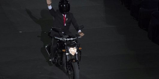 Presiden Joko Widodo mengendarai motor sambil melambaikan tangan saat pembukaan Asian Games ke-18 tahun 2018 di Stadion Utama Gelora Bung Karno, Jakarta, Sabtu (18/8/2018).