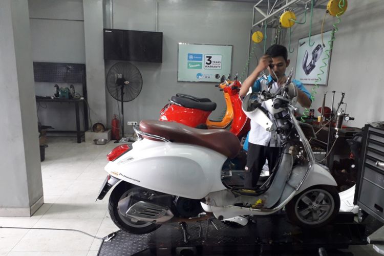 Salah seorang mekanik sedang melayani perbaikan salah satu unit Vespa di bengkel resmi Vespa di Jalan Margonda, Depok, Jumat (29/6/2018).