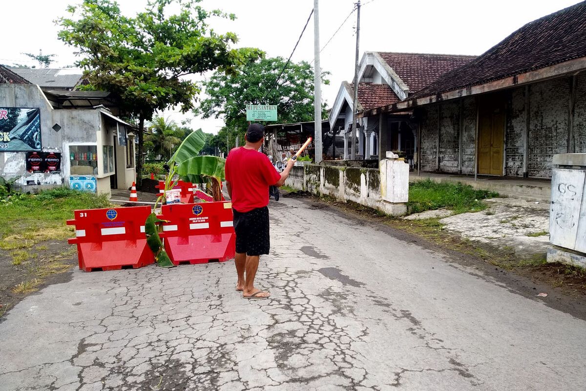 Warga Kelurahan Tanggung, Kota Blitar, menutup dan menjaga bagian jalan rusak yang dengan swadaya mereka perbaiki dengan pengecoran, Senin (14/2/2022)