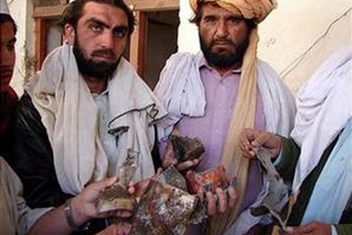 Beberapa warga Pakistan mengambil kepingan rudal dari rumah yang hancur dihantam dalam serangan udara AS di dekat Mir Ali, distrik Waziriztan Utara, 24 Januari 2009. 