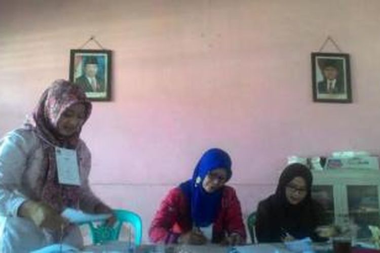 Petugas PPS sedang mengecek surat suara Pemilukada Wonosobo di TPS 1 Dusun Peniron, Talunombo, Wonosobo Rabu (9/12/2015), dengan latar belakang foto mantan Presiden SBY dan wakilnya Boediono