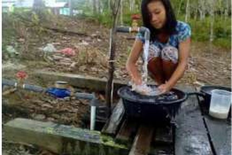 Seorang warga Desa Mantan dan Desa Menapar di Kalimantan Barat tengah menikmati air bersih yang disediakan PT Kartika Prima Cipta (KPC) atau salah satu unit usaha dari PT Sinar Mas Agro Resources and Technology Tbk (PT SMART).