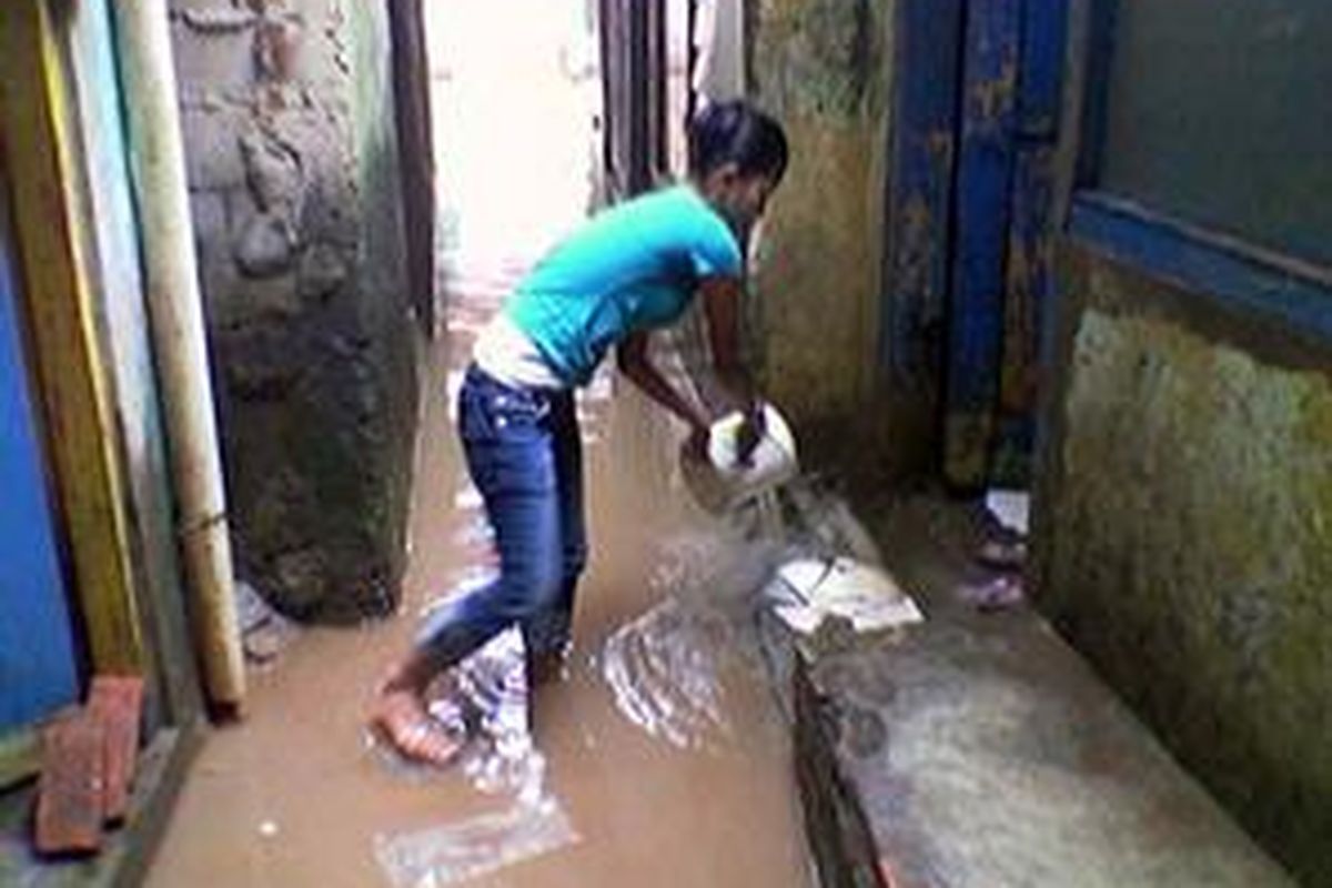 Seorang warga RT 16 RW 02, Kampung Pulo membersihkan rumahnya yang terendam banjir, Sabtu (8/3).