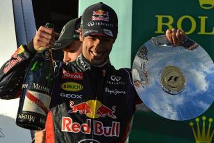 Pebalap Australia Daniel Ricciardo mengangkat trofi dan champagne di atas podium Sirkuit Albert Park, Melbourne, setelah finis kedua pada GP Australia, Minggu (16/3/2014).